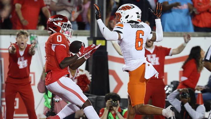 Oct 17, 2026; Houston, Texas, USA; Houston Cougars wide receiver Amare Thomas (0) makes a reception for a touchdown as Oklahoma State Cowboys safety Christian Bodnar (6) defends during the third quarter at TDECU Stadium. Mandatory Credit: Troy Taormina-Imagn Images