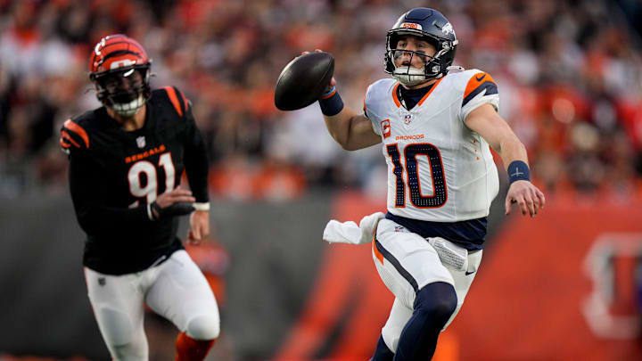 Denver Broncos quarterback Bo Nix (10) throws on the run as he is pressured by Cincinnati Bengals defensive end Trey Hendrickson (91) in the first quarter of the NFL Week 17 game between the Cincinnati Bengals and the Denver Broncos at Paycor Stadium in downtown Cincinnati on Saturday, Dec. 28, 2024.