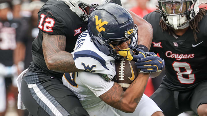 Nov 1, 2025; Houston, Texas, USA; West Virginia Mountaineers running back Diore Hubbard (20) is tackled by Houston Cougars linebacker Sione Fotu (12) in the first half at TDECU Stadium. Mandatory Credit: Thomas Shea-Imagn Images