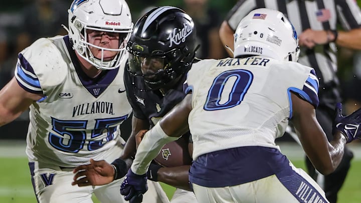 Sep 16, 2023; Orlando, Florida, USA; UCF Knights quarterback Timmy McClain (9) carries the ball against Villanova Wildcats defensive back Isas Waxter (0) and defensive lineman Jake Reichwein (55) during the second half at FBC Mortgage Stadium.
