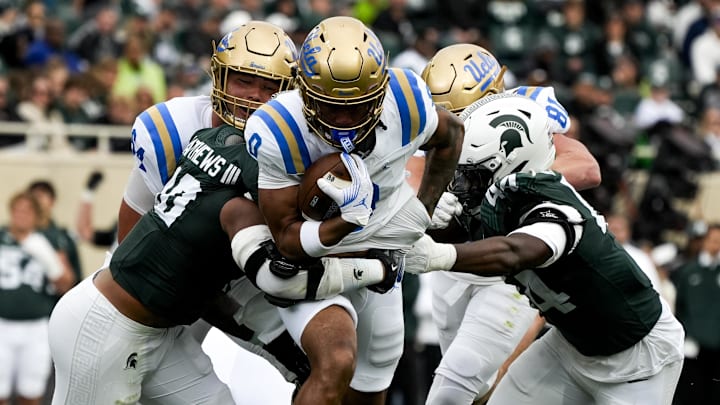 Oct 11, 2025; East Lansing, Michigan, USA; UCLA Bruins running back Jalen Berger (0) runs through the Michigan State defense in the second quarter at Spartan Stadium. Mandatory Credit: Brendan Mullin-Imagn Images