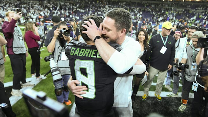 Dec 7, 2024; Indianapolis, IN, USA; Oregon Ducks head coach Dan Lanning hugs quarterback Dillon Gabriel (8) after defeating the Penn State Nittany Lions to win the Big Ten Championship in the 2024 Big Ten Championship game at Lucas Oil Stadium. Mandatory Credit: Robert Goddin-Imagn Images