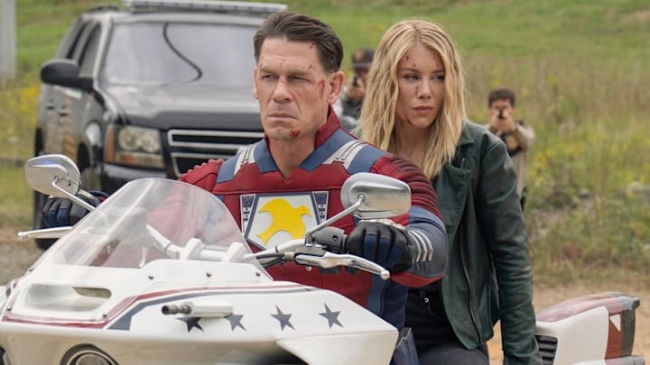 John Cena as Christopher Smith / Peacemaker and Jennifer Holland as Emilia Harcourt in Peacemaker season 2. 