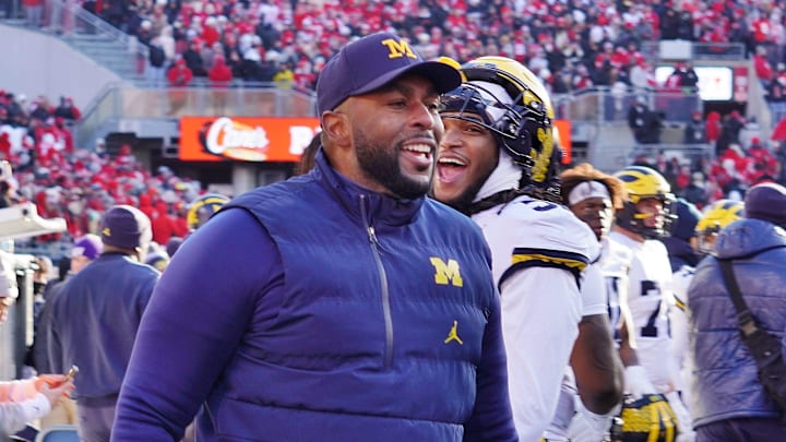 Michigan Wolverines coach Sherrone Moore returns to the sideline after waving goodbye to Ohio State fans at the end of his team's 13-10 victory.