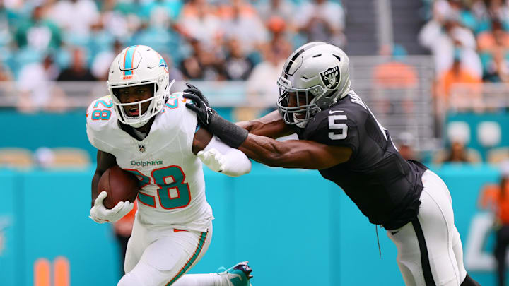 Nov 17, 2024; Miami Gardens, Florida, USA; Miami Dolphins running back De'Von Achane (28) runs with the football past Las Vegas Raiders linebacker Divine Deablo (5) during the first quarter at Hard Rock Stadium. Mandatory Credit: Sam Navarro-Imagn Images