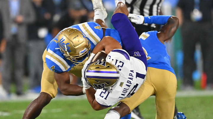 Sep 30, 2022; Pasadena, California, USA;  Washington Huskies wide receiver Denzel Boston (12) is stopped by UCLA Bruins defensive back Stephan Blaylock (4) defensive back Mo Osling III (7) after a 15 yard gain and first down in the first quarter at the Rose Bowl. Mandatory Credit: Jayne Kamin-Oncea-Imagn Images