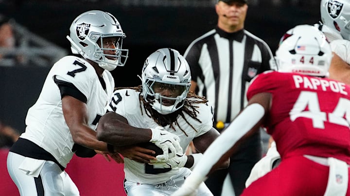 Raiders quarterback Geno Smith (7) hands the ball off to running back Ashton Jeanty (2) against the Cardinals during a preseason game at State Farm Stadium in Glendale on Aug. 23, 2025.