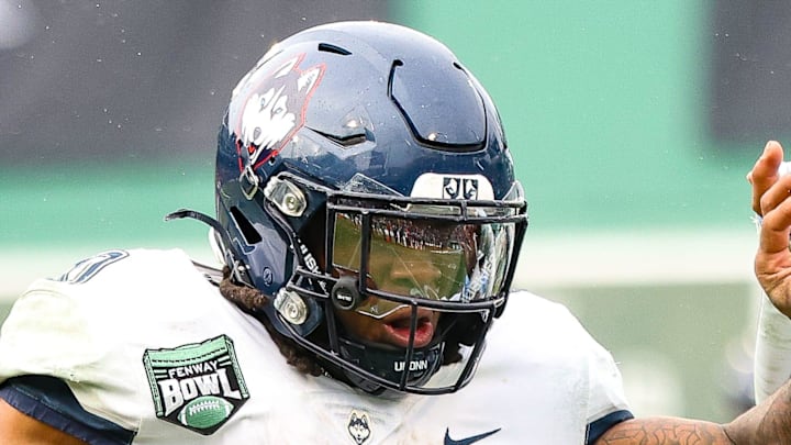 UConn's Cam Edwards stiff-arms North Carolina's Tyrane Stewart during the third annual Wasabi Fenway Bowl at Fenway Park on Saturday, Dec. 28, 2024.