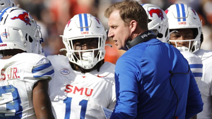 Southern Methodist Mustangs coach Rhett Lashlee (center) huddles with players during a stoppage in play in the first half against the Virginia Cavaliers at Scott Stadium .