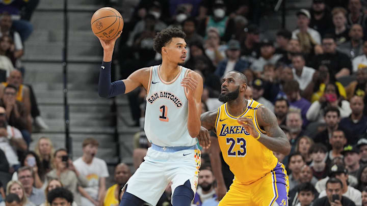 San Antonio Spurs center Victor Wembanyama looks to pass the ball while Los Angeles Lakers forward LeBron James guards him.