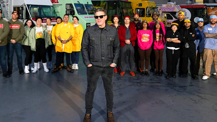 Nishaan, Fat Kid Food Co., Stop Drop N Roll, Rising Tiger, Good Fortune Company, Eat My Biscuits, Burger Walla, G’s Cheesesteaks and Cooking with Que team members in front of their trucks with host Tyler Florence, as seen on The Great Food Truck Race, Season 18.