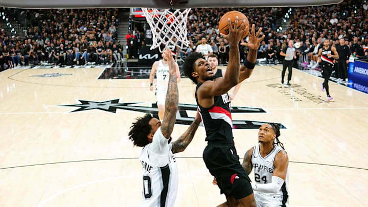 Apr 21, 2026; San Antonio, Texas, USA; Portland Trail Blazers guard Scoot Henderson (00) drives between forward Julian Champagnie (30) and guard Devin Vassell (24) during the first half of Game 2 of the first round of the 2026 NBA Playoffs against the San Antonio Spurs at Frost Bank Center.