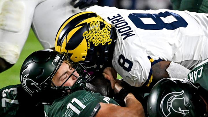 Michigan State quarterback Alessio Milivojevic, bottom, is sacked by Michigan Wolverines defensive end Derrick Moore 