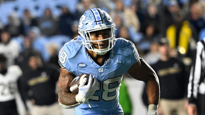 Nov 16, 2024; Chapel Hill, North Carolina, USA; North Carolina Tar Heels running back Omarion Hampton (28) runs as Wake Forest Demon Deacons defensive back Evan Slocum (7) defends in the fourth quarter at Kenan Memorial Stadium. Mandatory Credit: Bob Donnan-Imagn Images
