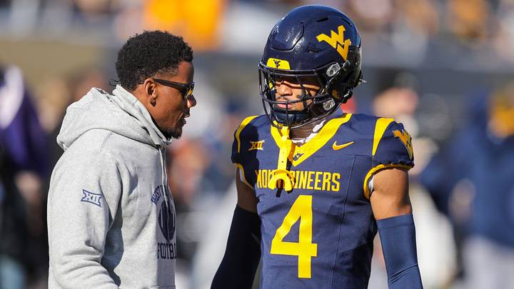Nov 29, 2025; Morgantown, West Virginia, USA; West Virginia Mountaineers wide receiver Cam Vaughn (4) talks to West Virginia Mountaineers assistant coach Pat White during warmups prior to their game against the Texas Tech Red Raiders at Milan Puskar Stadium. Mandatory Credit: Ben Queen-Imagn Images
