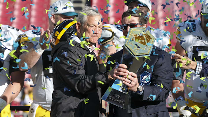 Dec 31, 2025; Tampa, FL, USA; Iowa Hawkeyes head coach Kirk Ferentz is given the ReliaQuest Bowl trophy after beating the Vanderbilt Commodores at Raymond James Stadium. Mandatory Credit: Nathan Ray Seebeck-Imagn Images