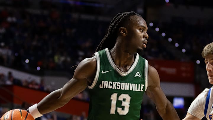 Nov 7, 2024; Gainesville, Florida, USA; Jacksonville Dolphins guard Robert McCray V (13) dribbles at Florida Gators forward Alex Condon (21) during the first half at Exactech Arena at the Stephen C. O'Connell Center. Mandatory Credit: Matt Pendleton-Imagn Images