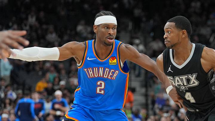 Mar 2, 2025; San Antonio, Texas, USA;  San Antonio Spurs guard De'Aaron Fox (4) dribbles against Oklahoma City Thunder guard Shai Gilgeous-Alexander (2) in the first half at Frost Bank Center. Mandatory Credit: Daniel Dunn-Imagn Images