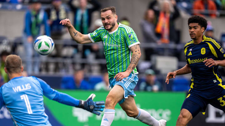 Apr 19, 2025; Seattle, Washington, USA;  Seattle Sounders forward Jordan Morris (13) takes a shot against Nashville SC goalkeeper Joe Willis (1) and defender Chris Applewhite (33) during the second half at Lumen Field. Mandatory Credit: Stephen Brashear-Imagn Images