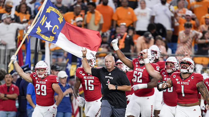 Sep 7, 2024; Charlotte, North Carolina, USA; North Carolina State Wolfpack head coach Dave Doeren leads his team onto the field against the Tennessee Volunteers during the first quarter at the Dukes Mayo Classic at Bank of America Stadium. Mandatory Credit: Jim Dedmon-Imagn Images
