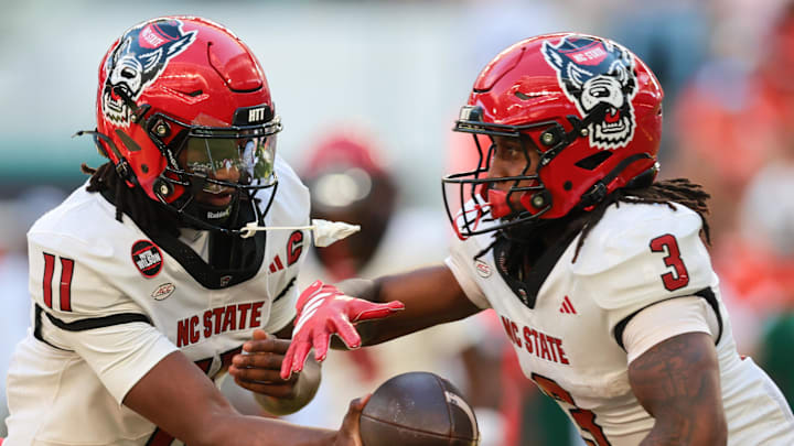 Nov 15, 2025; Miami Gardens, Florida, USA; NC State Wolfpack quarterback CJ Bailey (11) hands off the football to running back Hollywood Smothers (3) during the first quarter at Hard Rock Stadium. Mandatory Credit: Sam Navarro-Imagn Images