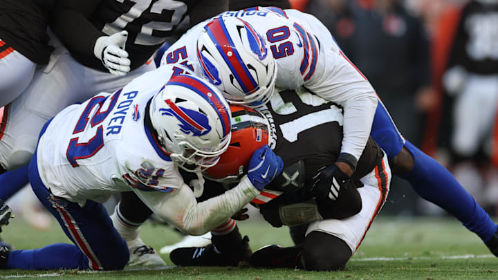 Dec 21, 2025; Cleveland, Ohio, USA; Cleveland Browns quarterback Shedeur Sanders (12) is sacked by Buffalo Bills safety Jordan Poyer (21) and defensive end Greg Rousseau (50) during the second half at Huntington Bank Field.
