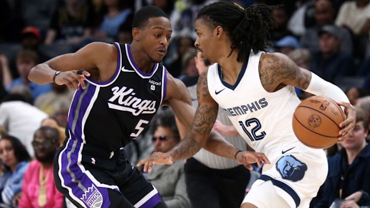 Dec 31, 2023; Memphis, Tennessee, USA; Memphis Grizzlies guard Ja Morant (12) dribbles as Sacramento Kings guard De'Aaron Fox (5) defends during the first half at FedExForum. Mandatory Credit: Petre Thomas-Imagn Images