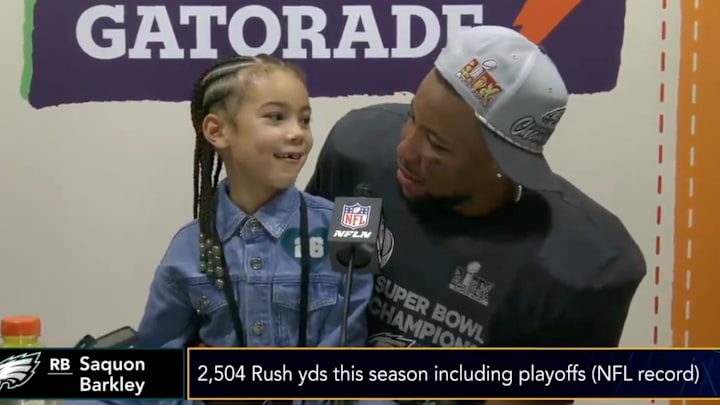Philadelphia Eagles running back Saquon Barkley sits at the Super Bowl LIX podium with his daughter Jada.