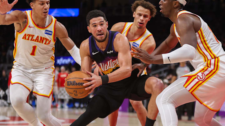 Jan 23, 2026; Atlanta, Georgia, USA; Phoenix Suns guard Devin Booker (1) is defended by Atlanta Hawks forward Jalen Johnson (1) and guard Dyson Daniels (5) and forward Onyeka Okongwu (17) in the second quarter at State Farm Arena. Mandatory Credit: Brett Davis-Imagn Images
