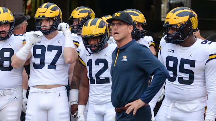 Head coach Jim Harbaugh of the Michigan Wolverines waits with offensive lineman Andrew Vastardis #68 and defensive end Aidan Hutchinson #97 and quarterback Cade McNamara #12 and defensive lineman Donovan Jeter #95 to take the field against the Nebraska Cornhuskers at Memorial Stadium on October 9, 2021 in Lincoln, Nebraska