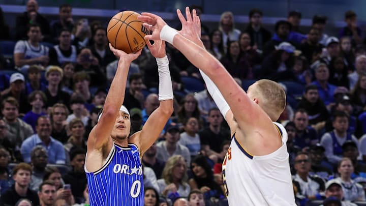Dec 27, 2025; Orlando, Florida, USA; Orlando Magic guard Anthony Black (0) shoots a three point basket against Denver Nuggets center Nikola Jokic (15) during the first quarter at Kia Center. Mandatory Credit: Mike Watters-Imagn Images
