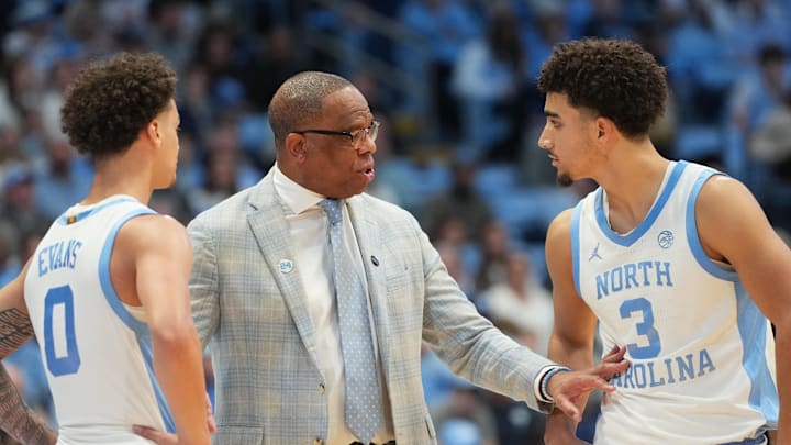 Dec 7, 2025; Chapel Hill, North Carolina, USA; North Carolina Tar Heels head coach Hubert Davis talks with guard Kyan Evans (0) and guard Derek Dixon (3) in the second half at Dean E. Smith Center. Mandatory Credit: Bob Donnan-Imagn Images