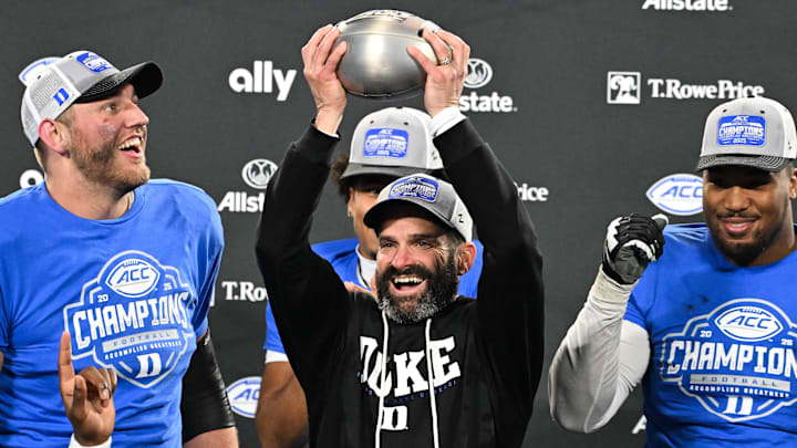Dec 6, 2025; Charlotte, NC, USA; Duke Blue Devils head coach Manny Diaz lifts the ACC trophy with offensive lineman Justin Pickett (77) and defensive tackle Aaron Hall (99) after defeating the Virginia Cavaliers at the 2025 ACC Championship game at Bank of America Stadium. Mandatory Credit: Bob Donnan-Imagn Images
