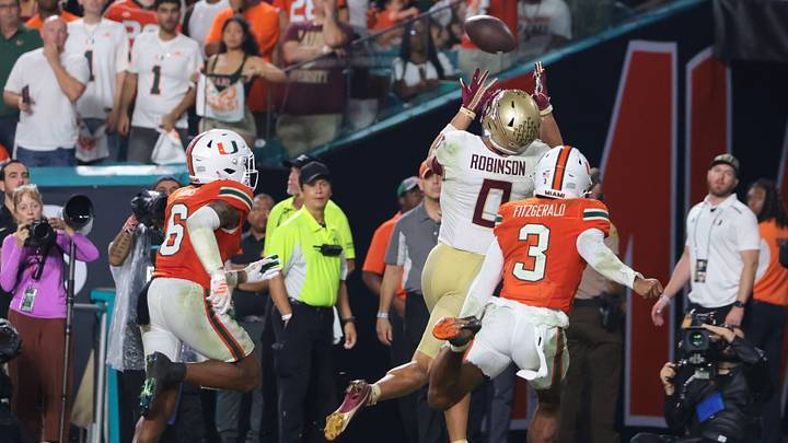 Oct 17, 2026; Miami Gardens, Florida, USA; Florida State Seminoles wide receiver Duce Robinson (0) catches a touchdown during overtime against Miami Hurricanes defensive back Bryce Fitzgerald (3) and defensive back Xavier Lucas (6) at Hard Rock Stadium. Mandatory Credit: Sam Navarro-Imagn Images Oct 17, 2026; Miami Gardens, Florida, USA; Florida State Seminoles wide receiver Duce Robinson (0) catches a touchdown during overtime against Miami Hurricanes defensive back Bryce Fitzgerald (3) and defensive back Xavier Lucas (6) at Hard Rock Stadium. Mandatory Credit: Sam Navarro-Imagn Images