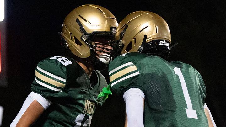 Iowa City West's Cooper Bruxvoort (18) and Cade Towler (1) celebrate after a Trojan touchdown Aug. 28, 2026 during an Iowa High School football game at Iowa City West High School in Iowa City, Iowa.