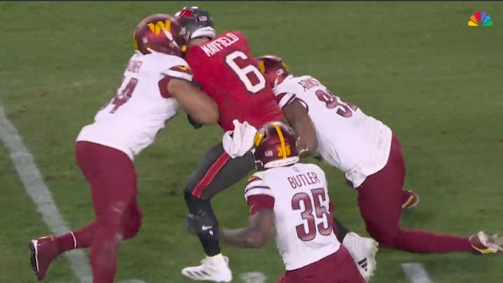 Baker Mayfield runs through multiple Washington Commanders defenders. 