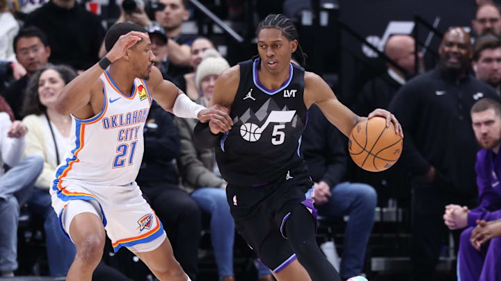 Feb 21, 2025; Salt Lake City, Utah, USA; Utah Jazz forward Cody Williams (5) dribbles against Oklahoma City Thunder guard Aaron Wiggins (21) during the second quarter at Delta Center. Mandatory Credit: Rob Gray-Imagn Images