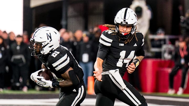 Nov 1, 2025; Lincoln, Nebraska, USA; Nebraska Cornhuskers quarterback TJ Lateef (14) hands the ball off to running back Emmett Johnson (21) against the Southern California Trojans during the fourth quarter at Memorial Stadium. Mandatory Credit: Dylan Widger-Imagn Images