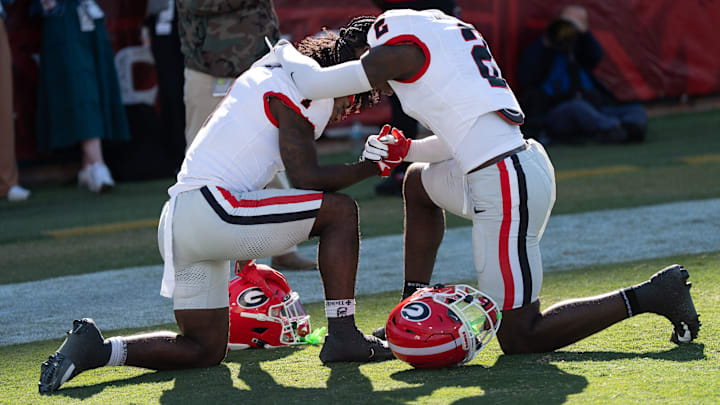 Georgia Bulldogs wide receiver Zachariah Branch (1) and Georgia Bulldogs running back Josh McCray (2) kneel for a prayer before the first quarter in an NCAA football game, Saturday, Nov. 1, 2025, at EverBank Stadium in Jacksonville, Fla.[Doug Engle/Florida Times-Union]