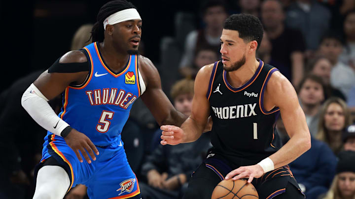 Jan 4, 2026; Phoenix, Arizona, USA; Oklahoma City Thunder guard Luguentz Dort (5) defends against Phoenix Suns guard Devin Booker (1) at Mortgage Matchup Center. Mandatory Credit: Mark J. Rebilas-Imagn Images