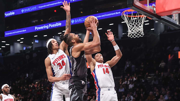 Jan 8, 2025; Brooklyn, New York, USA;  Brooklyn Nets forward Tosan Evbuomwan (12) looks to drive past Detroit Pistons forward Bobi Klintman (34) and guard Wendell Moore Jr. (14) in the fourth quarter at Barclays Center. Mandatory Credit: Wendell Cruz-Imagn Images