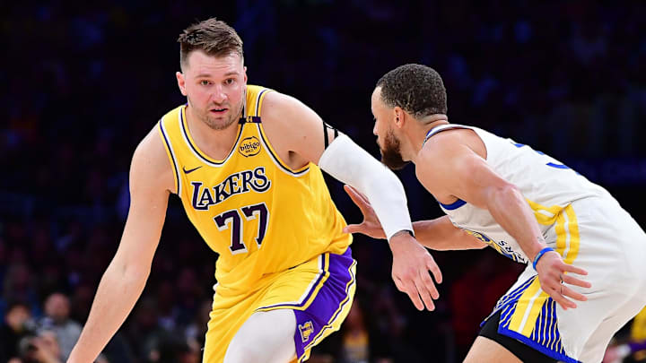 Apr 3, 2025; Los Angeles, California, USA; Los Angeles Lakers guard Luka Doncic (77) moves the ball against Golden State Warriors guard Stephen Curry (30) during the first half at Crypto.com Arena. Mandatory Credit: Gary A. Vasquez-Imagn Images