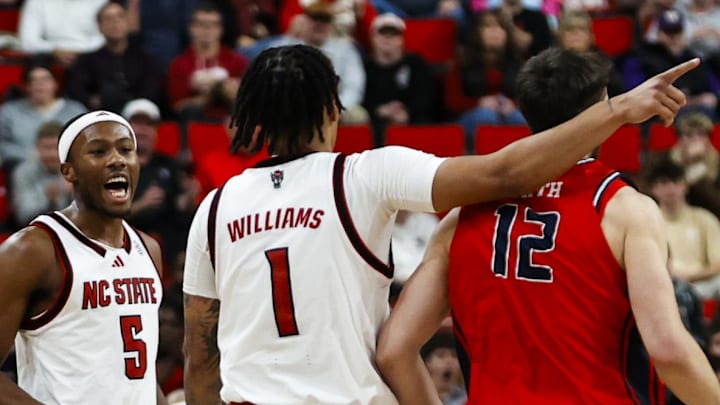 Dec 6, 2025; Raleigh, North Carolina, USA; NC State Wolfpack forward Darrion Williams (1) celebrates a 3-point shot over Liberty Flames forward Josh Smith (12) during the second half of the game at Lenovo Center. Mandatory Credit: Jaylynn Nash-Imagn Images