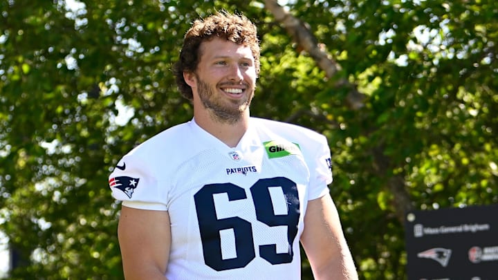 Jul 23, 2025; Foxborough, MA, USA; New England Patriots guard Cole Strange (69) delivers a puppy to a local family as part of the Patriots pet adoption event before training camp at Gillette Stadium. Mandatory Credit: Eric Canha-Imagn Images