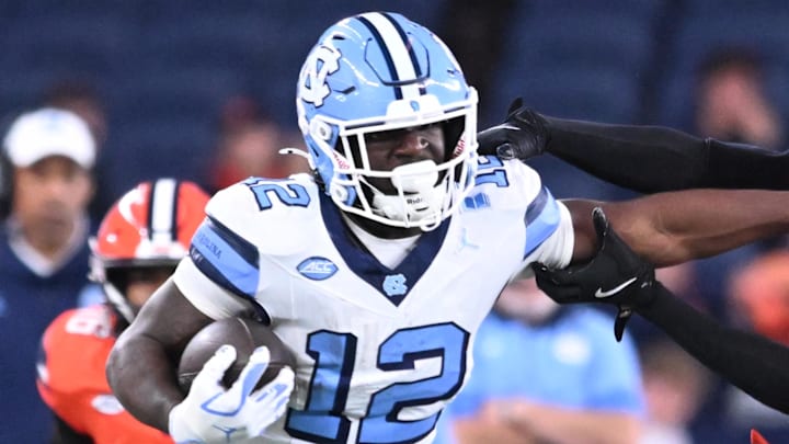 Oct 31, 2025; Syracuse, New York, USA; North Carolina Tar Heels running back Demon June (12) gives a stiff arm to Syracuse Orange defensive back Braheem Long Jr. (0) while scoring a touchdown in the third quarter at the JMA Wireless Dome. Mandatory Credit: Mark Konezny-Imagn Images