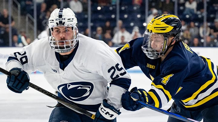Michigan and Penn State hockey players jostle for the puck. 