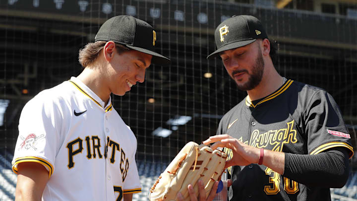 Jul 22, 2025; Pittsburgh, Pennsylvania, USA;  Seth Hernandez (left) the Pittsburgh Pirates first round and number six overall pick in the 2025 first year player draft looks at the glove of Pirates pitcher Paul Skenes (30) before the game against the Detroit Tigers at PNC Park. Mandatory Credit: Charles LeClaire-Imagn Images