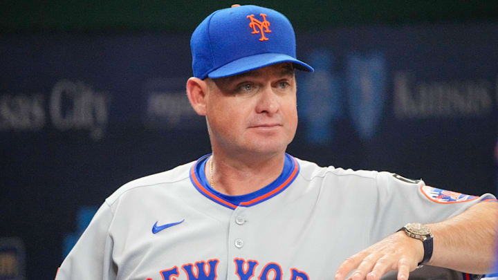Jul 11, 2025; Kansas City, Missouri, USA; New York Mets manager Carlos Mendoza (64) watches from the dugout against the Kansas City Royals prior to a game at Kauffman Stadium. Mandatory Credit: Denny Medley-Imagn Images