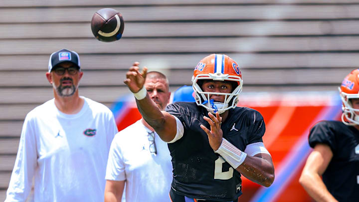 Florida Gators quarterback DJ Lagway throws a pass in front of quarterbacks coach Ryan O'Hara and head coach Billy Napier during position drills.