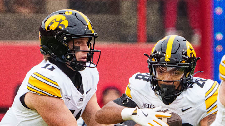 Nov 28, 2025; Lincoln, Nebraska, USA; Iowa Hawkeyes quarterback Mark Gronowski (11) hands the ball off to running back Kamari Moulton (28) against the Nebraska Cornhuskers during the first quarter at Memorial Stadium. Mandatory Credit: Dylan Widger-Imagn Images
